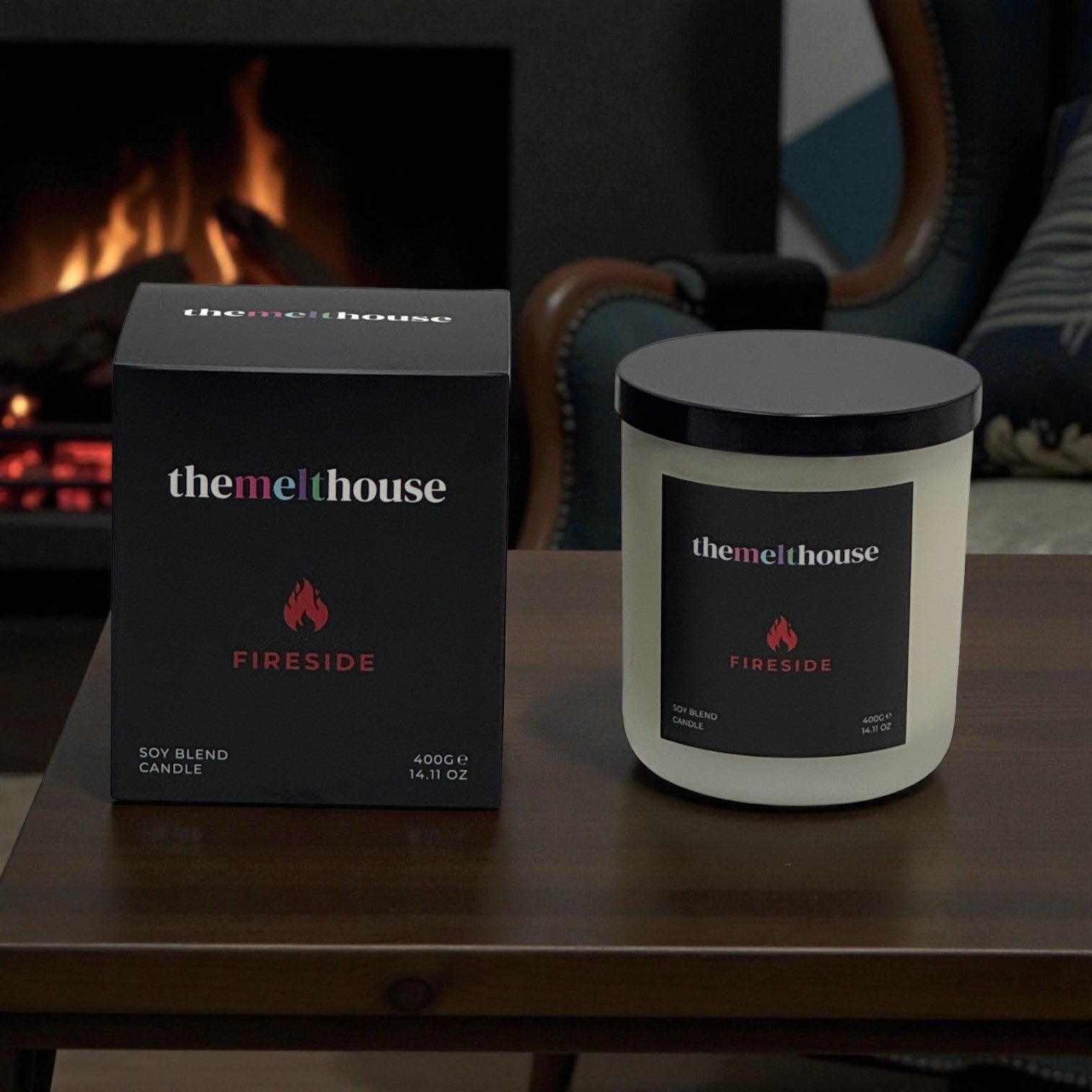 The Melthouse Fireside candle and packaging on a table with a fireplace in the background