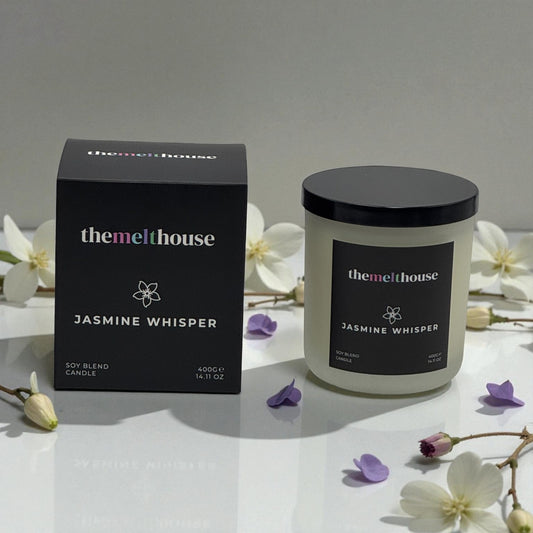 The Melthouse Jasmine Whisper candle and packaging on a white surface with flowers.