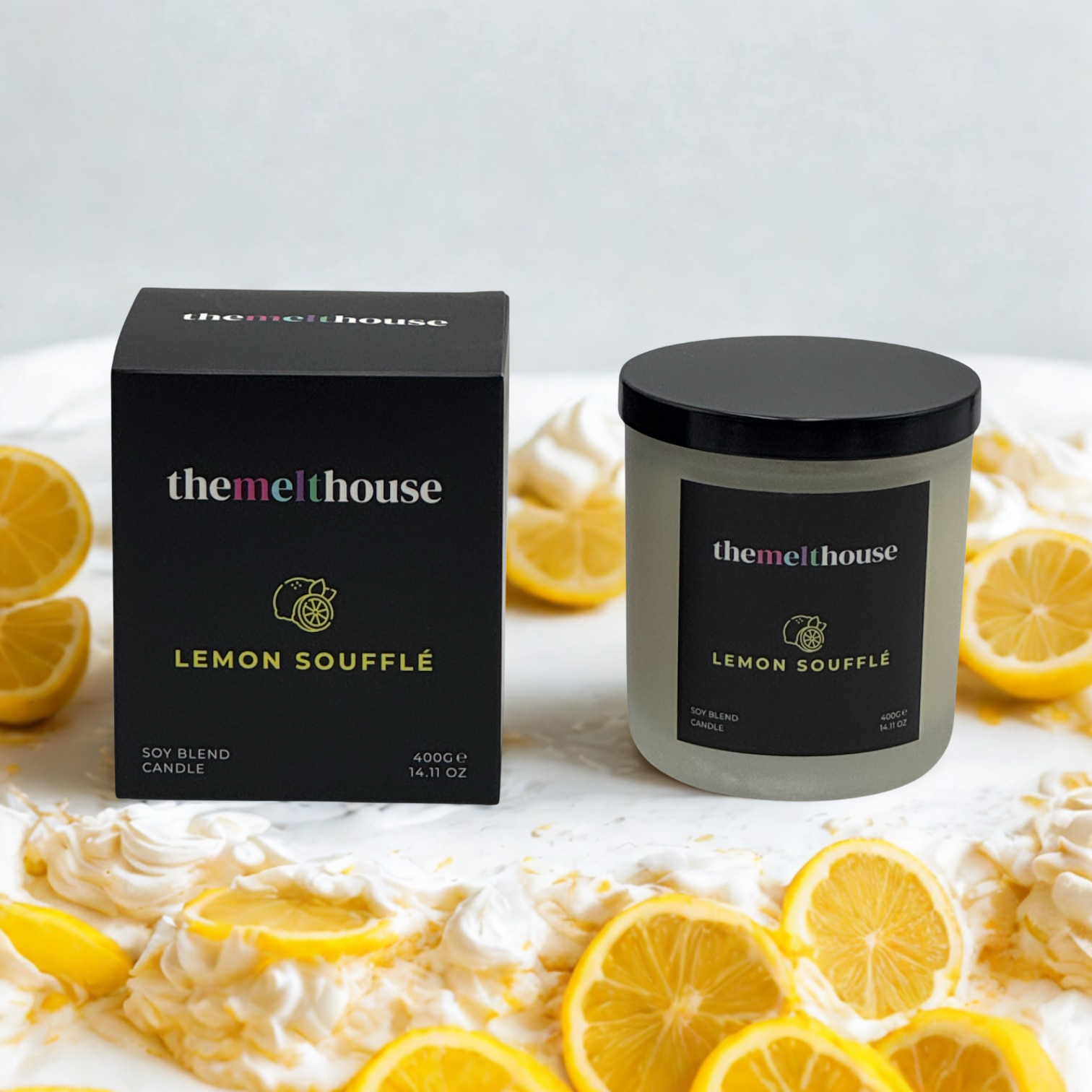 The Melthouse Lemon Souffle candle with packaging on a white surface with lemon slices.