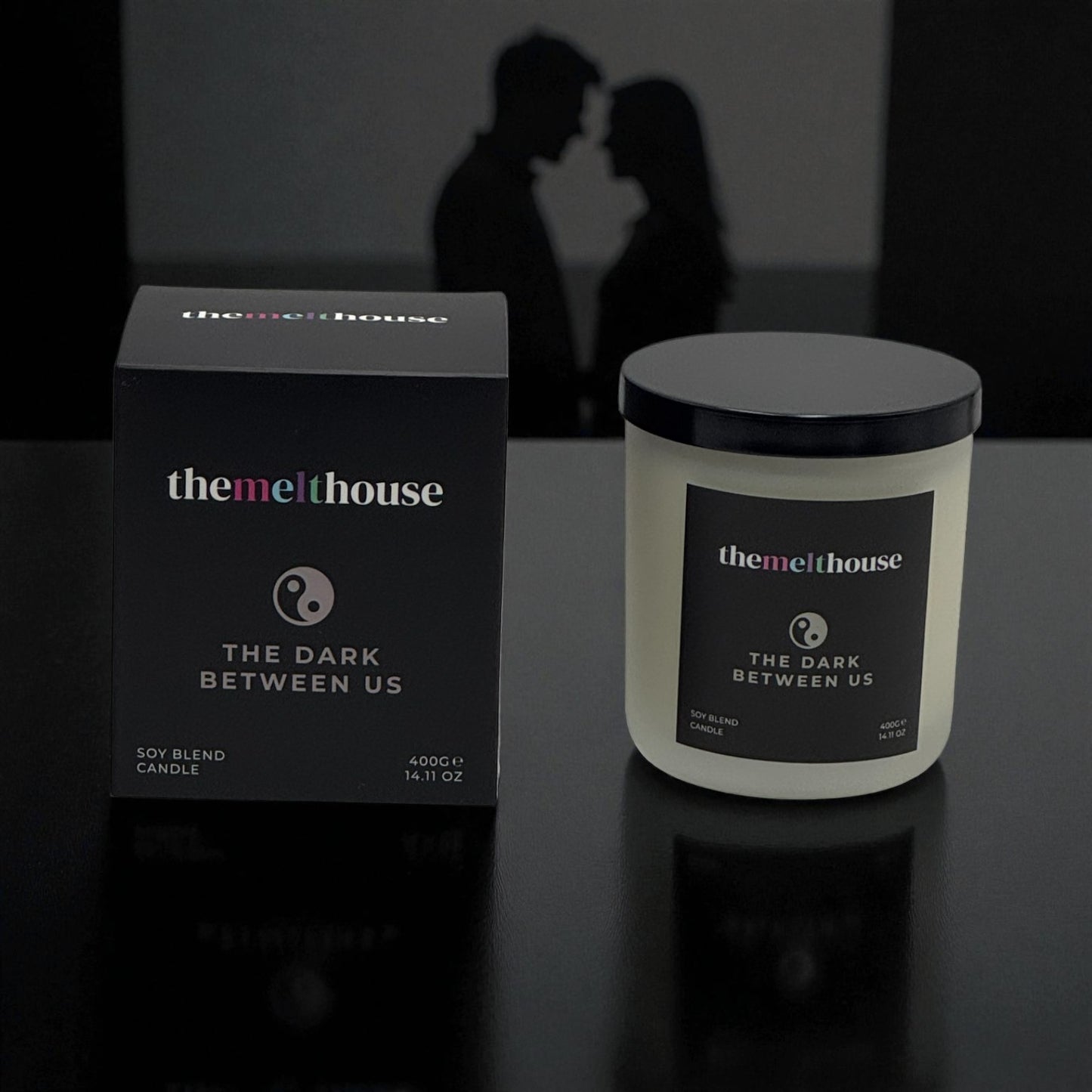 The Dark Between Us The Melthouse candle and packaging with a romantic silhouette in the background