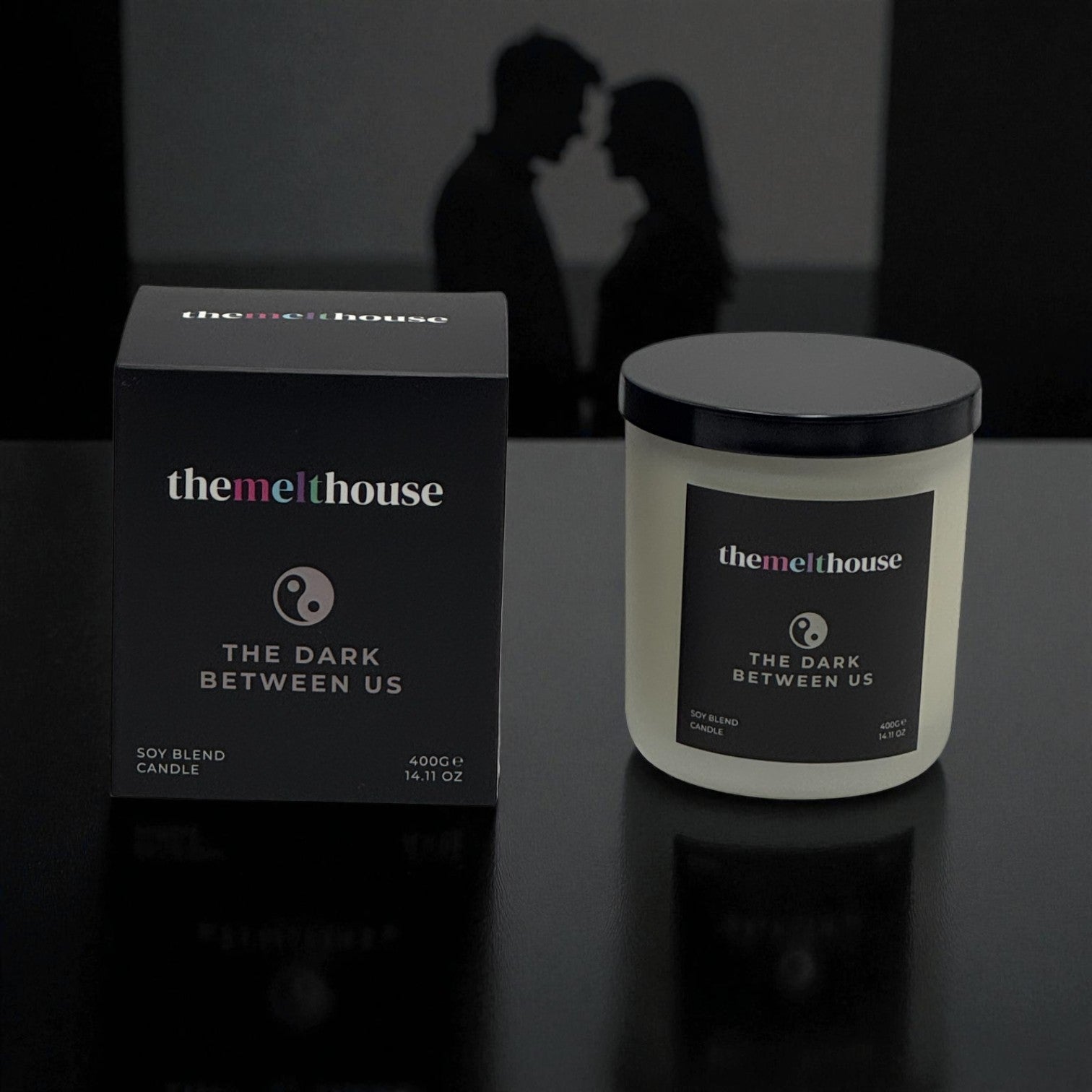 The Dark Between Us The Melthouse candle and packaging with a romantic silhouette in the background